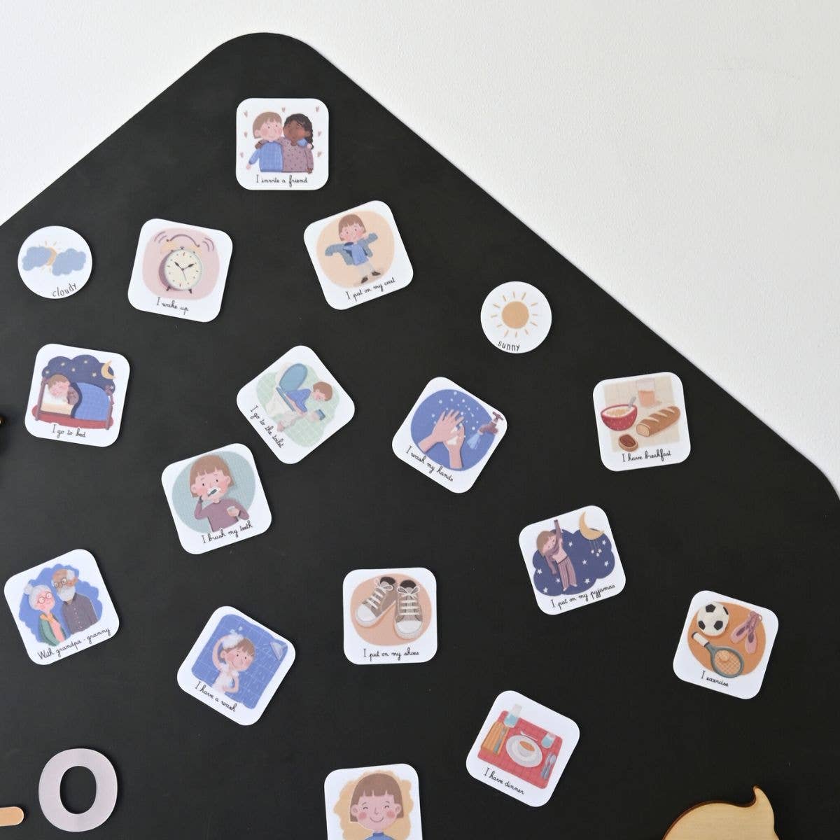 magnets routine en anglais éparpillés sur un tableau magnétique noir