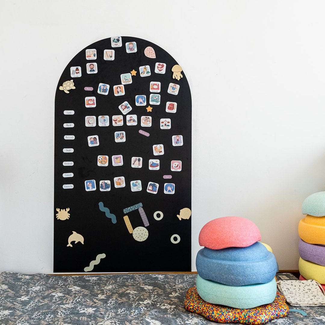 magnets routine et étoiles sur un tableau magnétique noir en arche à côté de jouets en bois