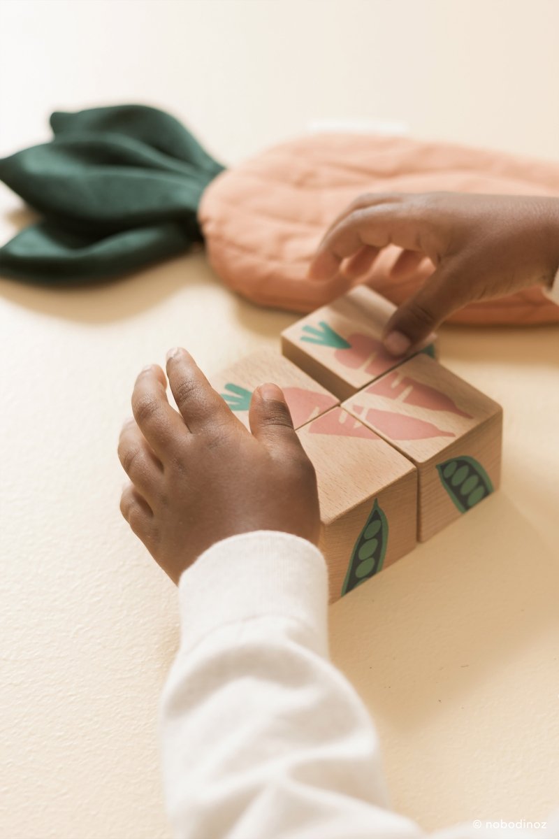 Nobodinoz Wooden Cubes - Veggies, a child's hands playing with the cubes