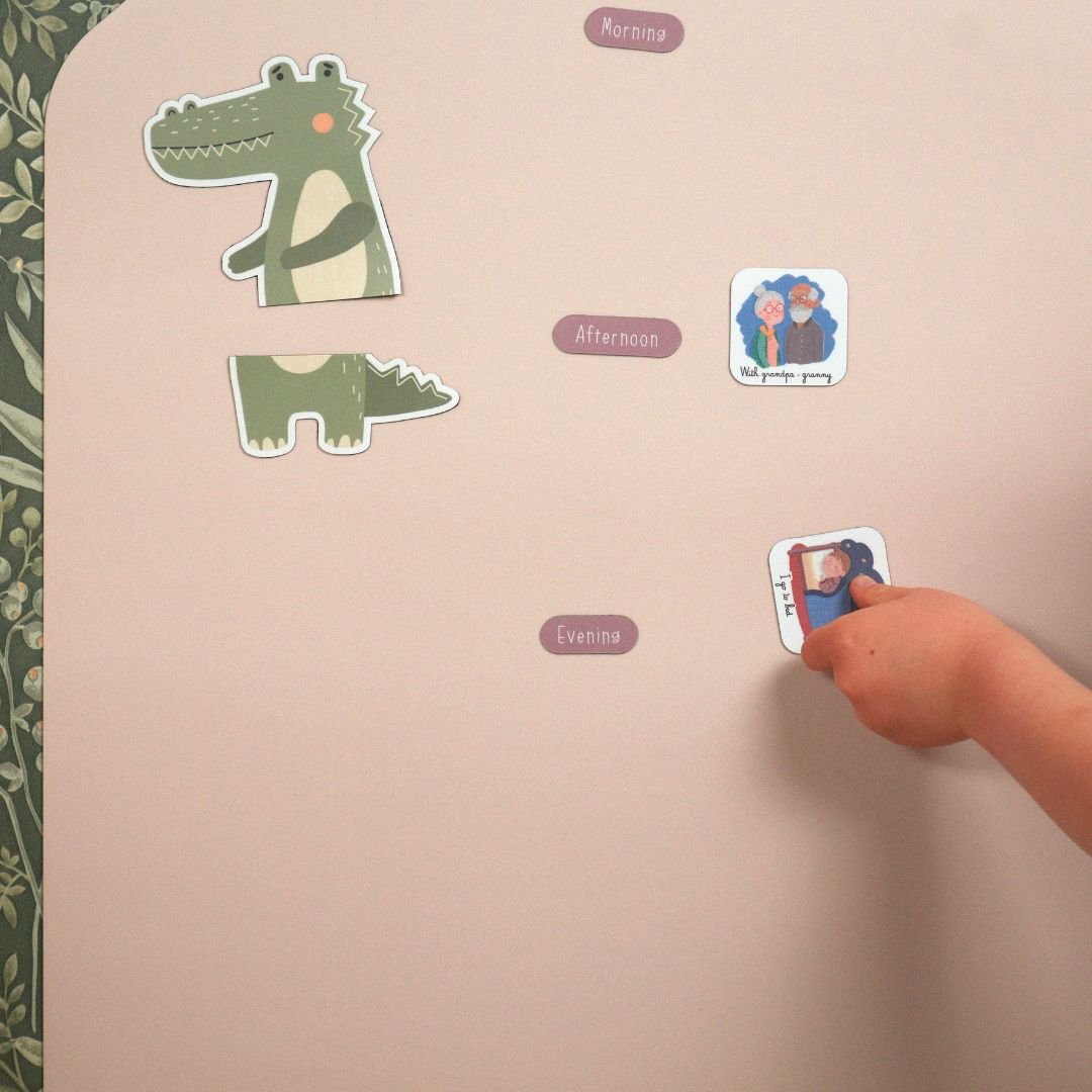 main d'enfant qui déplace un magnet routine sur un tableau rose avec matin, après-midi et soir