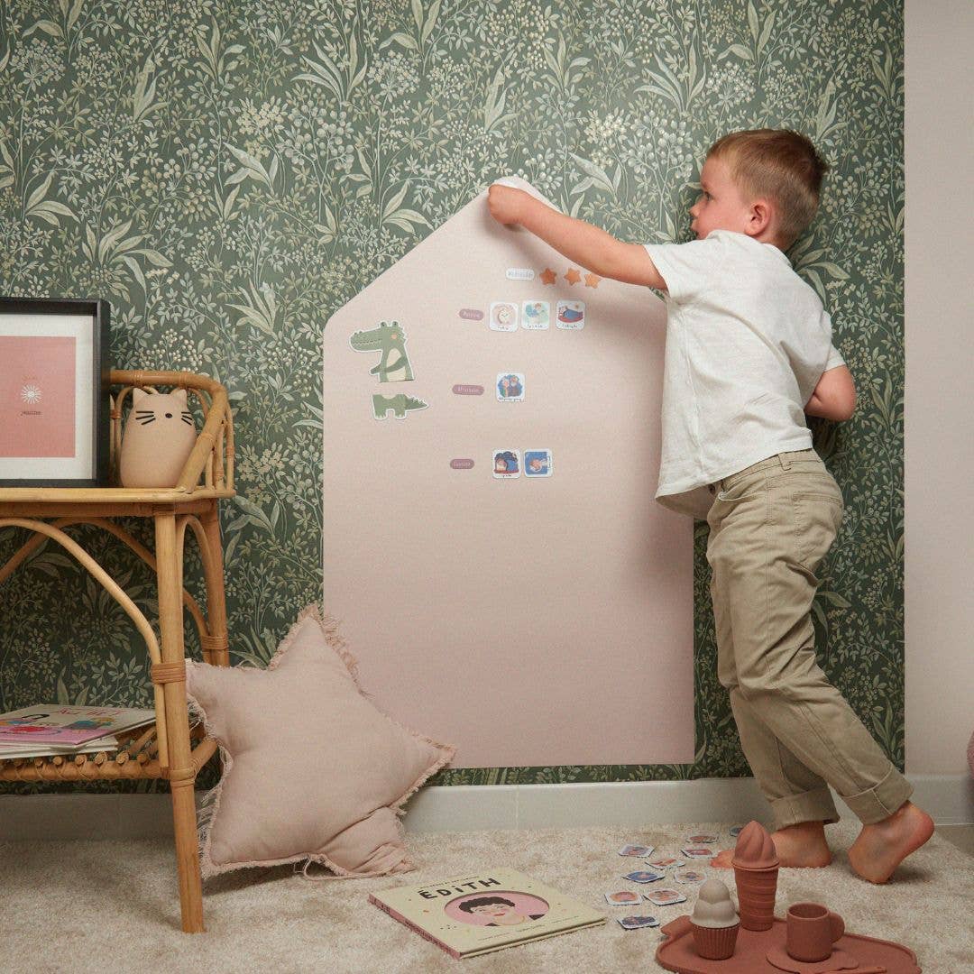 enfant qui colle des magnets routine ferflex sur un tableau rose en forme de maison