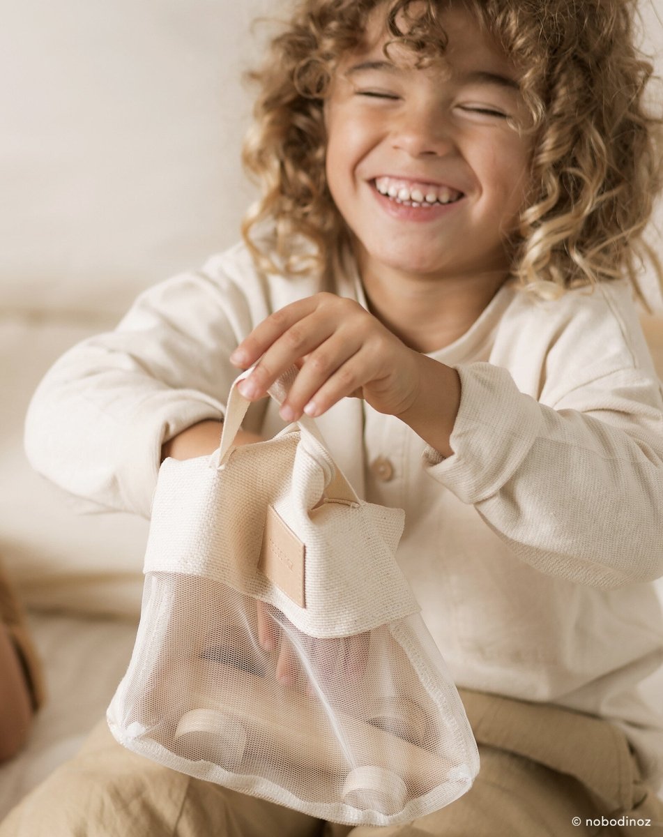 Nobodinoz Wooden Racing Car - Beech Wood, a child with the car's packaging